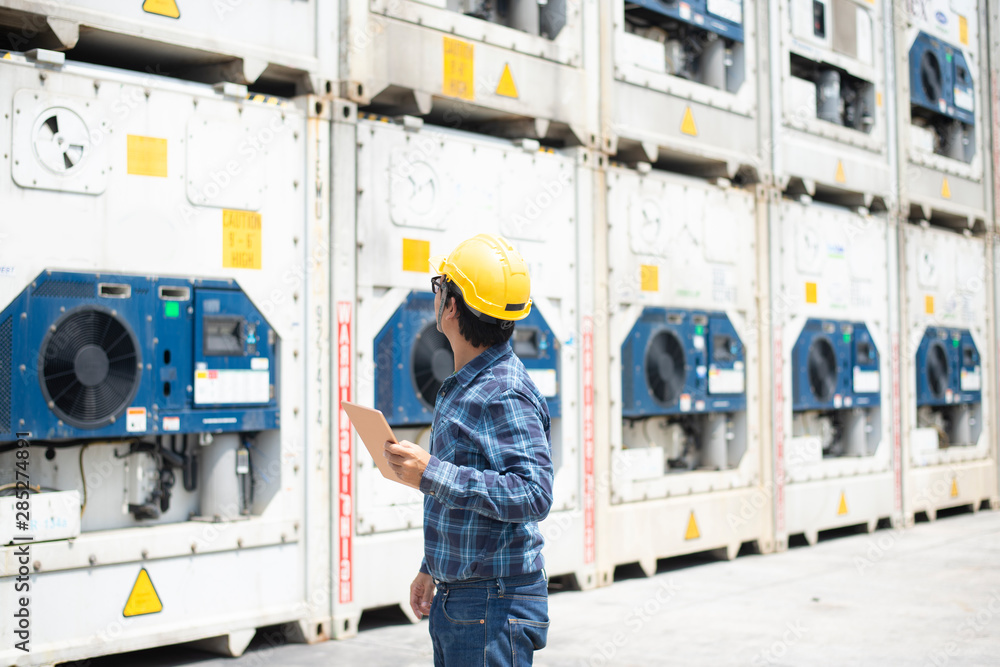 A reefer container technician is looking and take care of frozen or chill cargo with handling tablet while working in the storage yard. A reefer container technician is looking and take care of frozen or chill cargo with handling tablet while working in the storage yard.