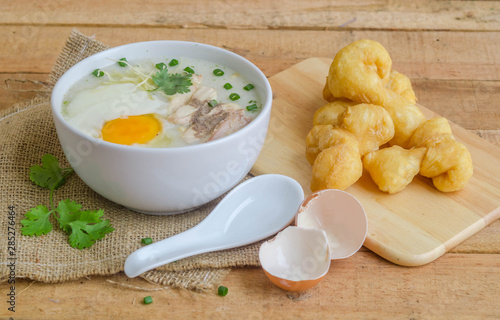 Porridge, chicken Porridge (congee) and Soft-boiled egg served in white bowl with deep-fried doughstick photo