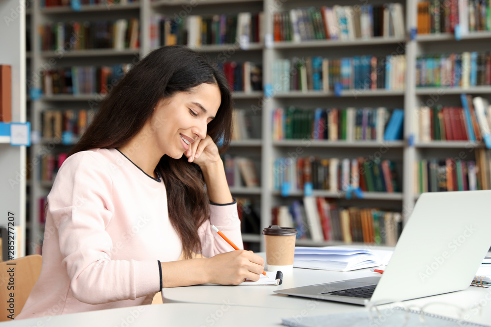 Young woman studying at table in library Young woman studying at table in library