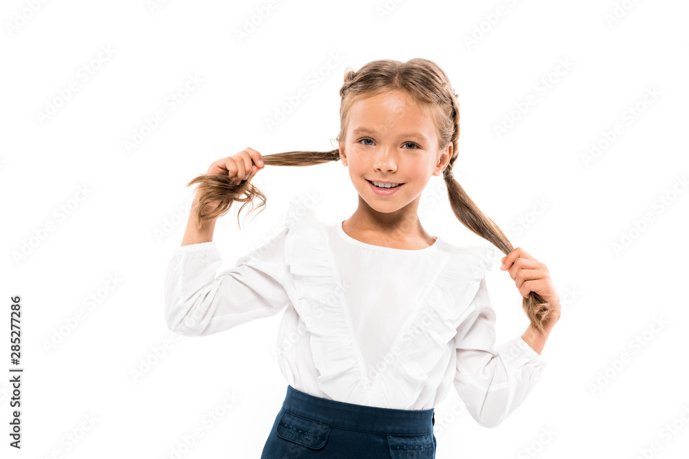 cheerful kid touching hair while looking at camera isolated on white cheerful kid touching hair while looking at camera isolated on white