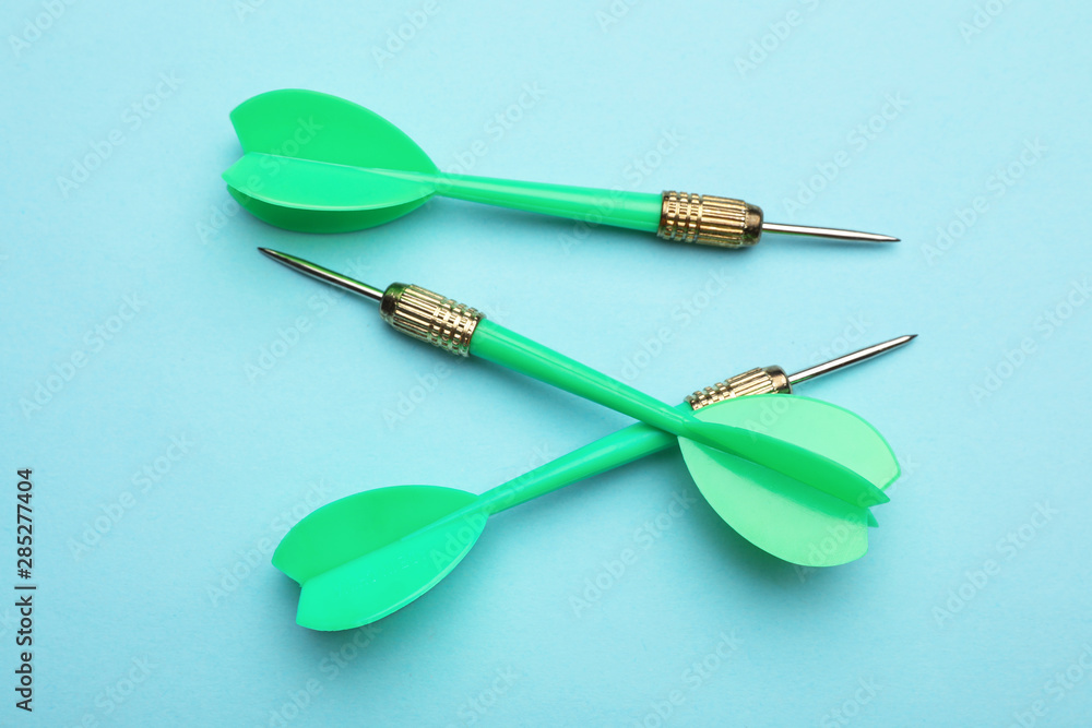 Green dart arrows on blue background, flat lay Green dart arrows on blue background, flat lay