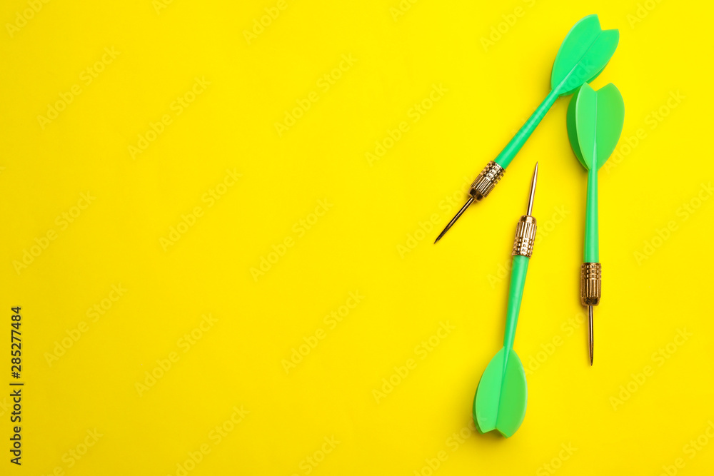 Green dart arrows on yellow background, flat lay with space for text Green dart arrows on yellow background, flat lay with space for text