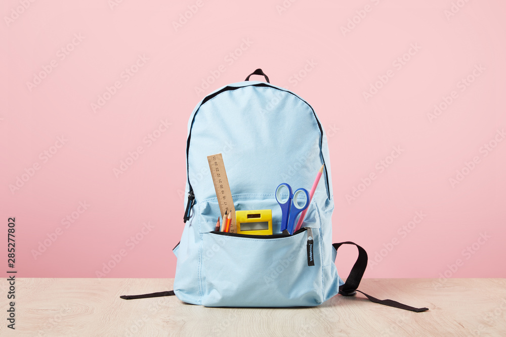 School blue backpack with stationery in pocket isolated on pink - obrazy, fototapety, plakaty 