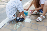 Cute child girl and boy draws with chalk on the asphalt. Asphalt street art. Kids education. Childhood