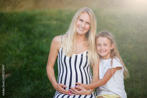 Image of pregnant woman and daughter outdoors © snedorez