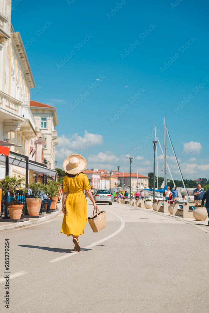 woman in yellow sundress walking by resort summer city