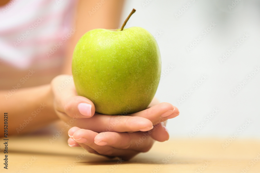 Woman holding fresh green apple at table, closeup. Space for text Woman holding fresh green apple at table, closeup. Space for text