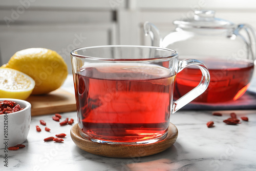 Healthy goji tea with lemon in glass cup on marble table