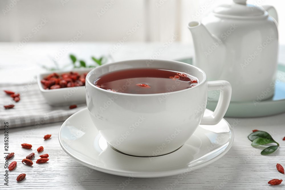 Healthy goji tea in cup on white wooden table Healthy goji tea in cup on white wooden table