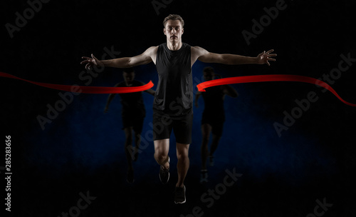 Runner wins by crossing the finish line on dark background