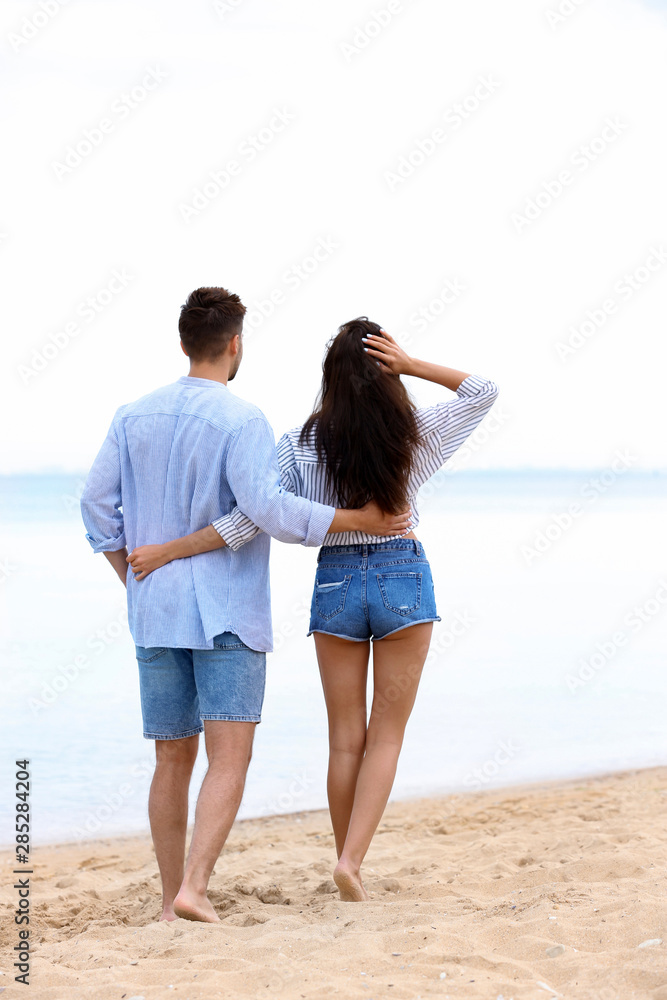 Happy young couple walking together on beach near sea Happy young couple walking together on beach near sea