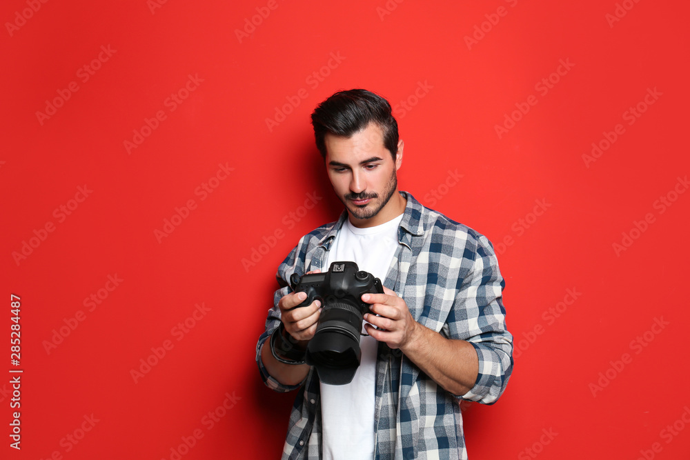 Young photographer with professional camera on red background Young photographer with professional camera on red background