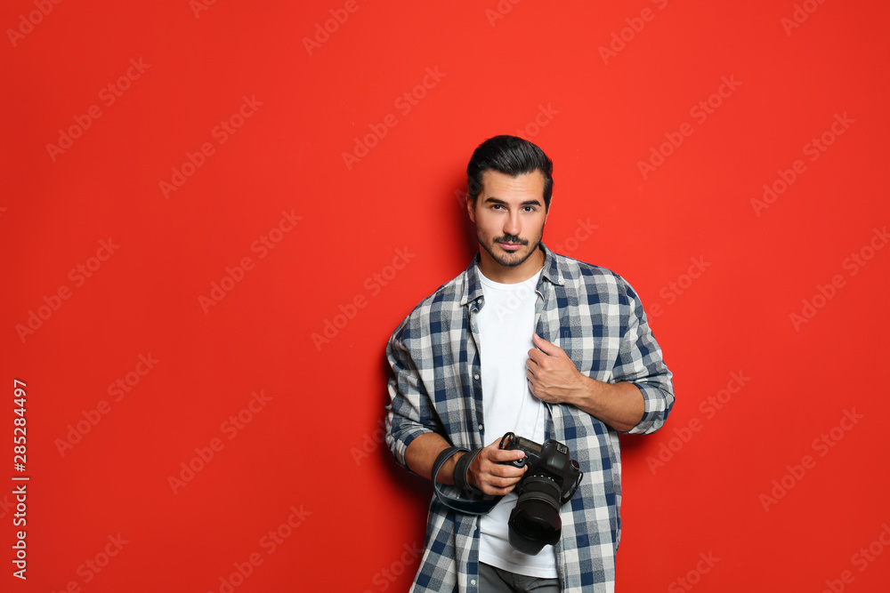 Young photographer with professional camera on red background. Space for text Young photographer with professional camera on red background. Space for text
