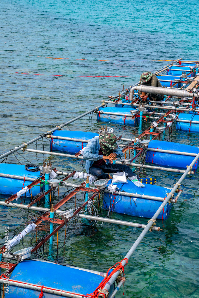 Workers settle and setup the waterworks fountain machine on the surface of the sea.