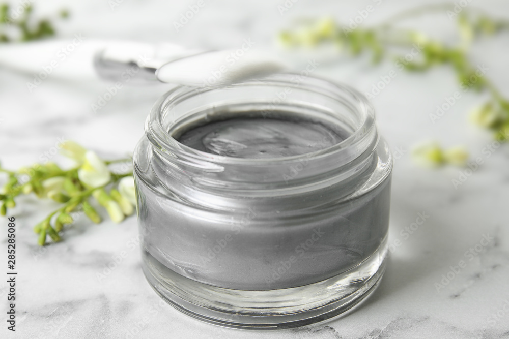 Professional face mask with brush and flowers on white marble table, closeup Professional face mask with brush and flowers on white marble table, closeup