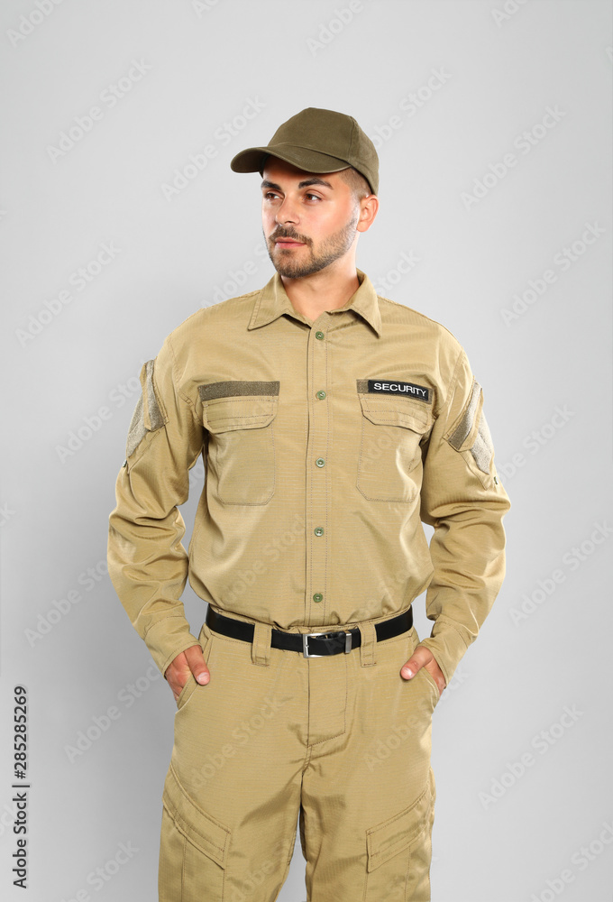 Male security guard in uniform on grey background Male security guard in uniform on grey background
