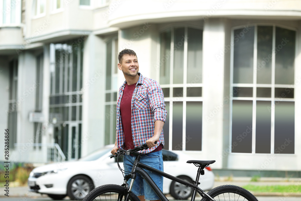 Handsome man with modern bicycle on city street