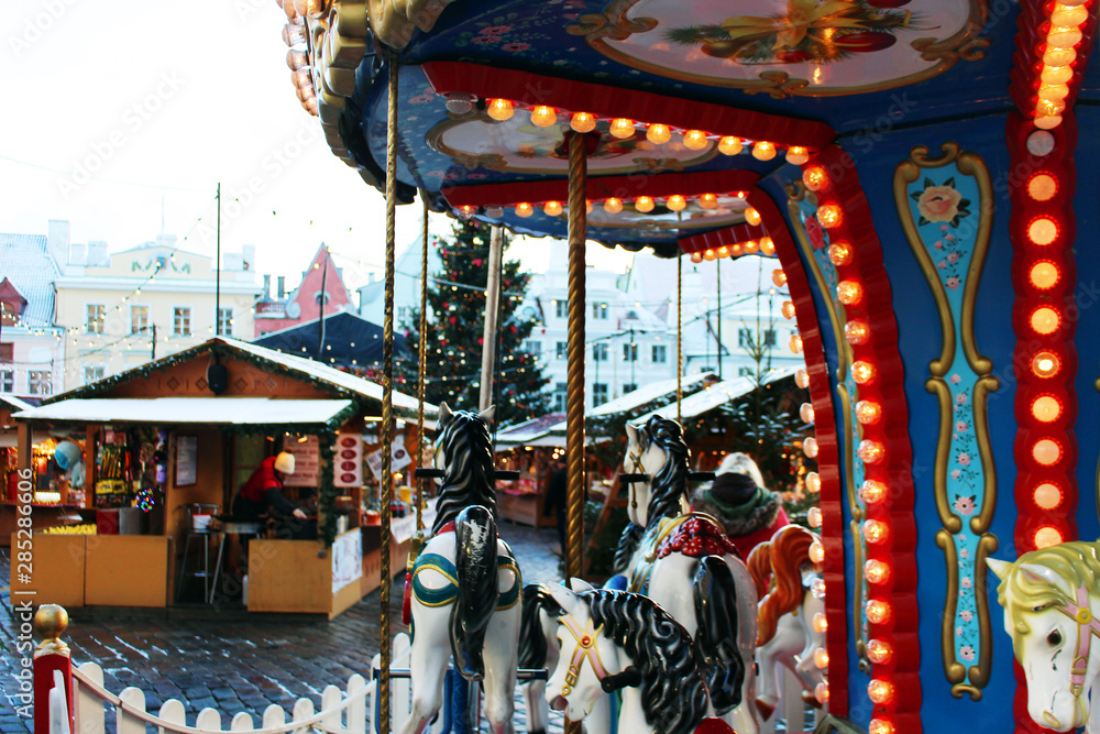 Carousel in Traditional Christmas market in Europe, Estonia. Carousel decorated with lights, Christmas fair concept.