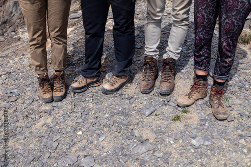 Company four tourists together feet in brown trekking hiking boots with laces on rocky cliff. Concept freedom, travel lifestyle adventure vacations, travelers outdoor wild nature summer sole