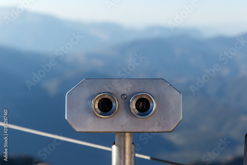 Public binocular telescope on the viewing platform against the background beautiful landscape in the mountains. Lovely view of the Taurus Mountains. Close-up. Kemer, Turkey photo