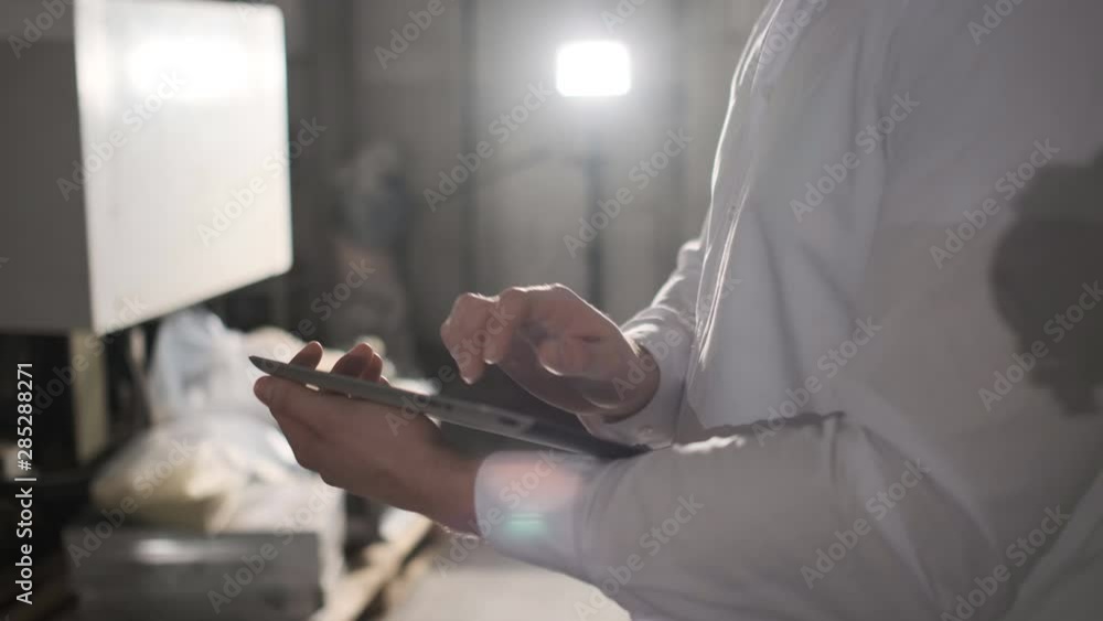 Engineer in hardhat is moving through a heavy industry factory with a tablet computer. Slow-Motion. 4k. Close-up