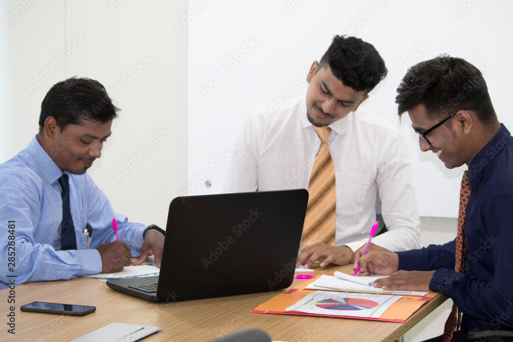 Three business colleagues writing notes during a meeting in conference room Three business colleagues writing notes during a meeting in conference room