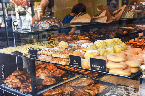 Display window of a bakery and pastry shop with assortment of different kinds of freshly baked artisan food. Authentic urban atmosphere