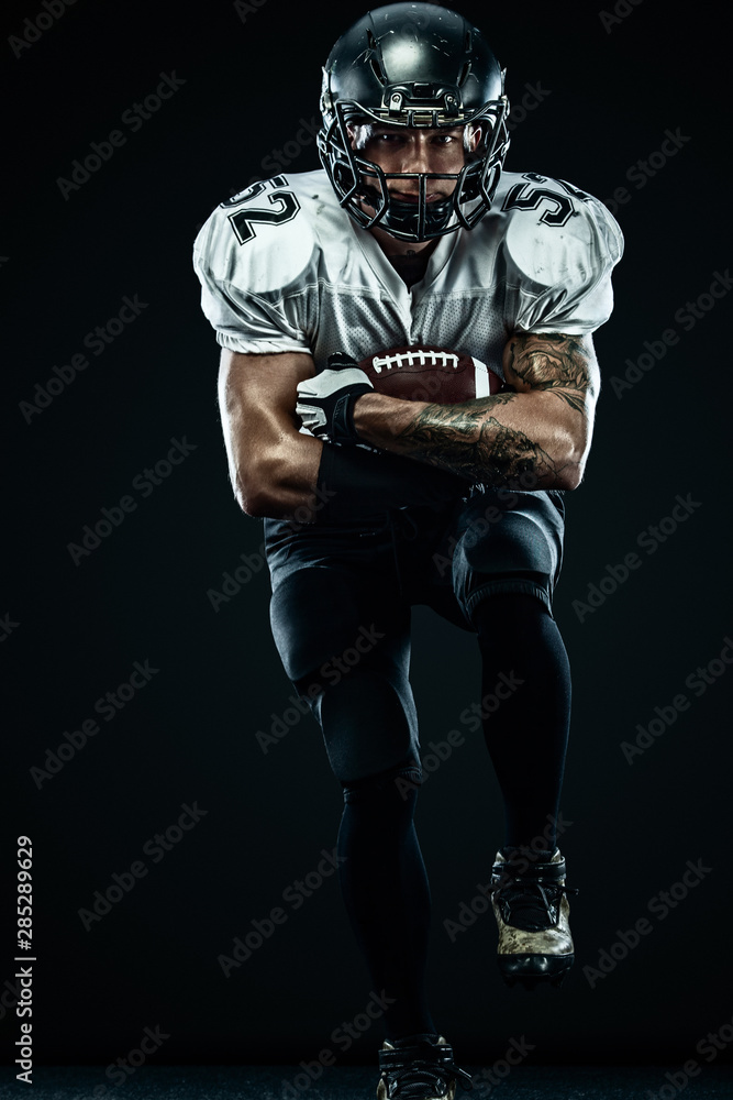 American football sportsman player in helmet isolated run in action on black background. Sport and motivation wallpaper. Team sports,
