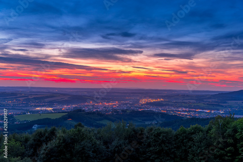 The setting sunset over the town of Valasske Mezirici as the city and its surroundings public light up slowly multi colored dark clouds and sun hiding below horizon.