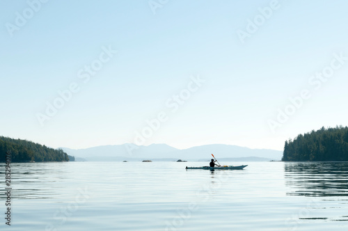 Scenic view of wide lake with man kayaking in the morning