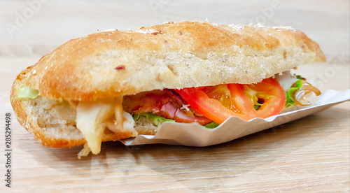 Ciabatta sandwich with lettuce, chicken and cheese on a wooden table