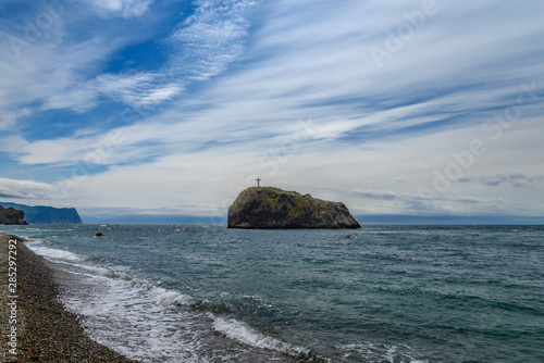 Rock with a cross stands in the sea