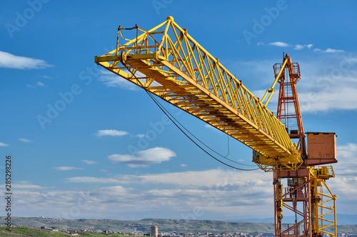 Yellow construction jib crane tower against blue sky photo