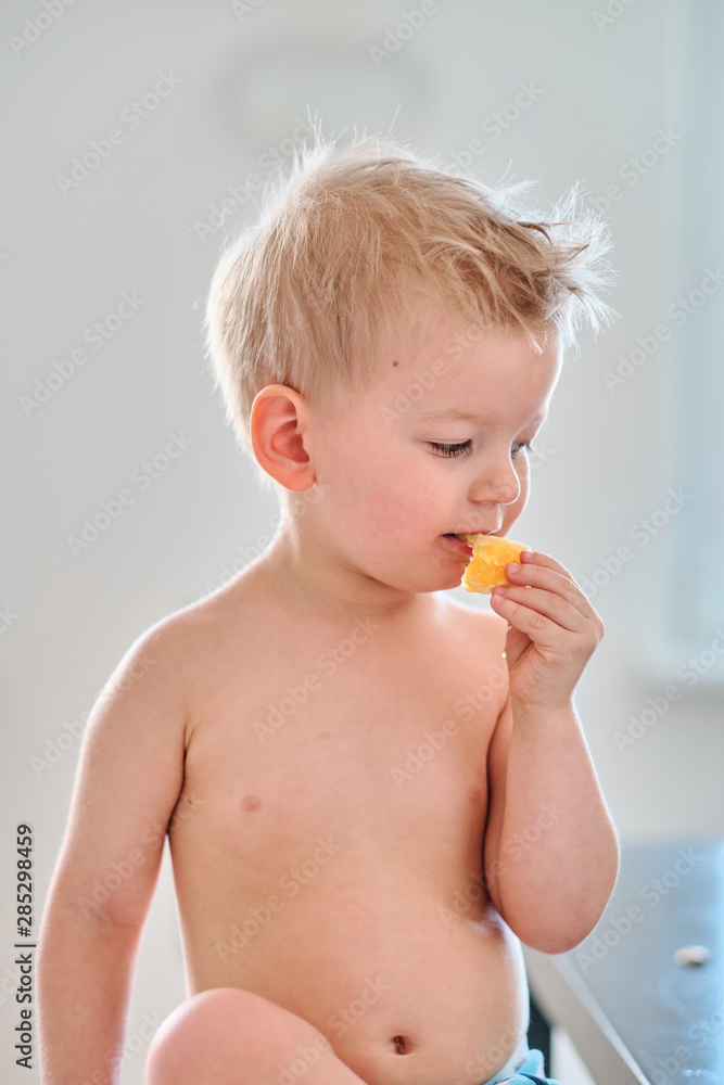 Two year old boy eating orange fruit