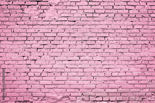 Bright trendy pink background of cracked brick wall