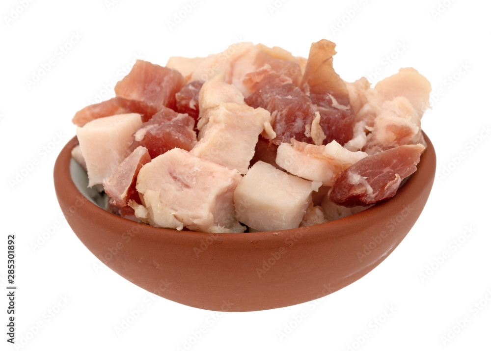 Pancetta sliced into cubes in a small bowl on a white background