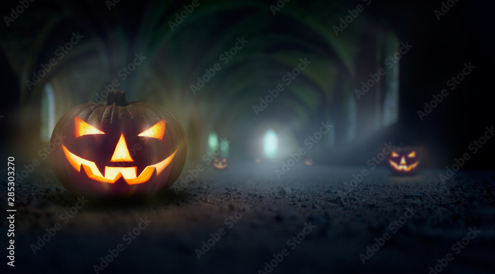 Naklejka premium Jack O' Lanterns in a cold, misty and dark blue spooky ruins of an old church, monastery