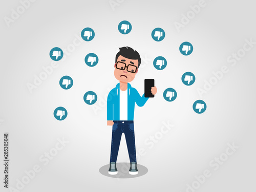 A sad young man looking at his mobile phone, surrounded by the thumbs down signs. Dislikes on the internet. Hate speech concept. Being dissapointed. Vector illustration, flat style, clip art. 