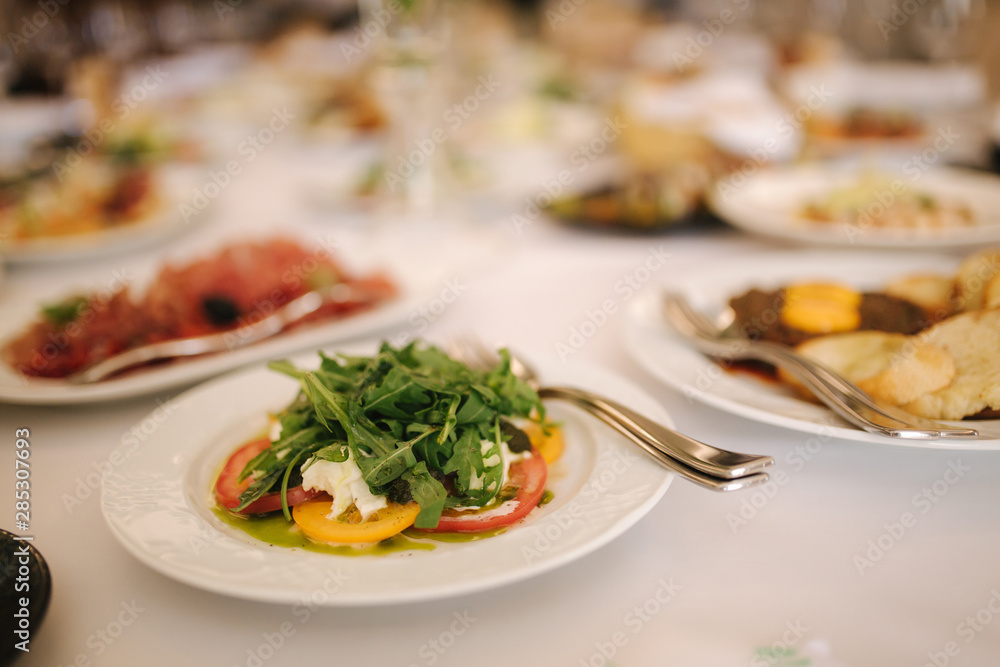 Fresh salad in restaurant on the table. Banquet concapt. Different salads with tomato, arugula, chicken, avocado, parmesan, shrimp Fresh salad in restaurant on the table. Banquet concapt. Different salads with tomato, arugula, chicken, avocado, parmesan, shrimp