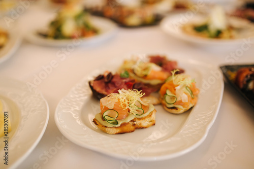 Appetizer in restaurant. Banquet concept. Bruschette with salmin and ham, decorated with basil and chile