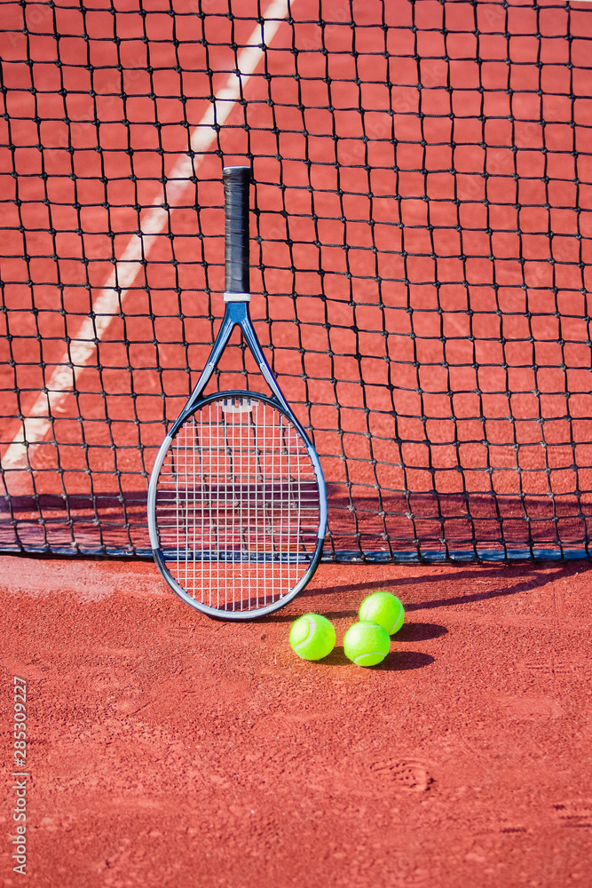 Tennis racket and balls against a net.