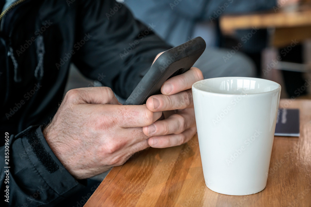 Man’s hands with smartphone and a white cup Man’s hands with smartphone and a white cup