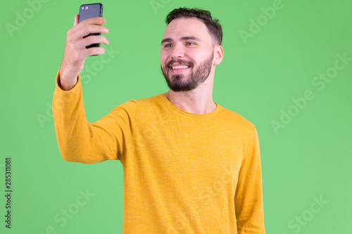Happy young handsome bearded man taking selfie