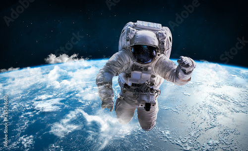Astronaut in the outer space over the planet Earth. Clouds on background. Spaceman. Elements of this image furnished by NASA
