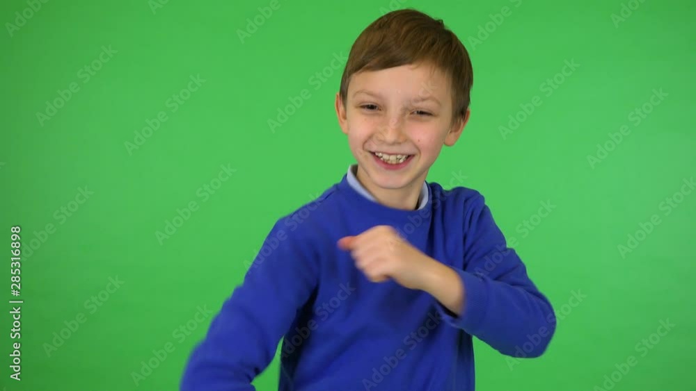 A young cute boy dances and smiles at the camera - green screen studio A young cute boy dances and smiles at the camera - green screen studio