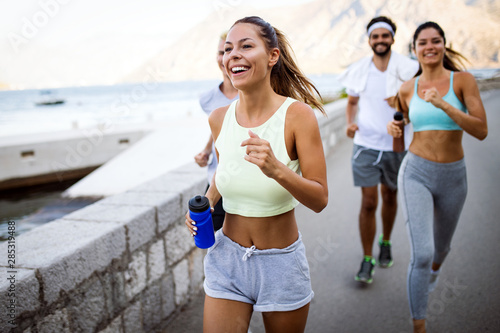 Fotografie Group of young people friends running outdoors at seaside