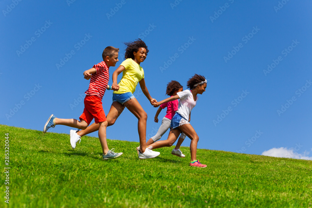 Four happy diverse looking children run on lawn Four happy diverse looking children run on lawn