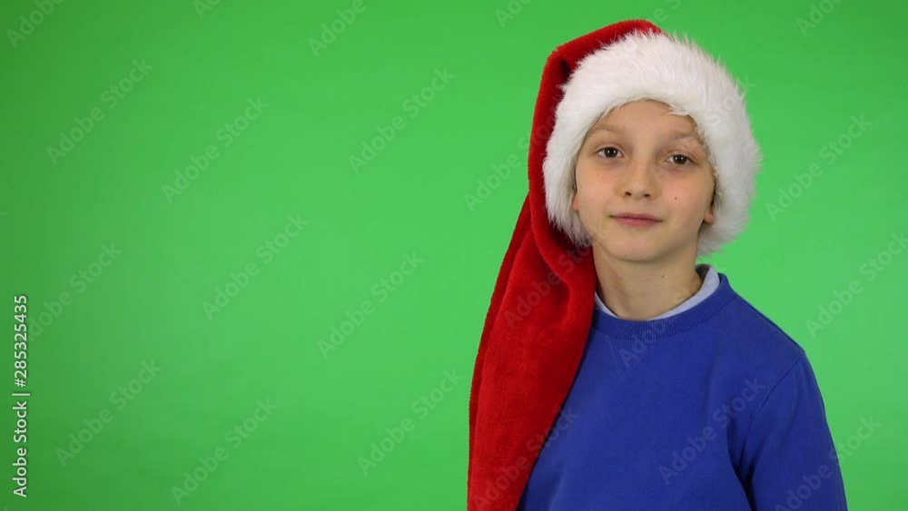 A young cute boy in a Christmas hat smiles at the camera - green screen studio A young cute boy in a Christmas hat smiles at the camera - green screen studio