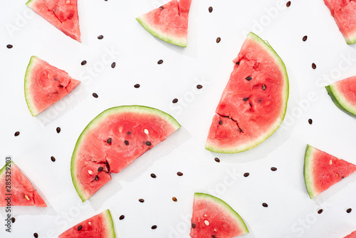top view of delicious juicy watermelon slices on white background with scattered seeds