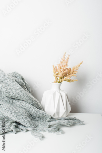 Small bouquet of flowers in vase with blanket